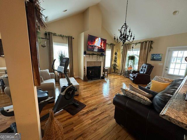 living room with high vaulted ceiling, light hardwood / wood-style flooring, and a notable chandelier