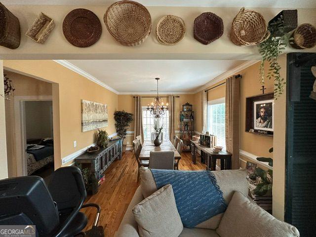 living room with ornamental molding, dark wood-type flooring, and a notable chandelier