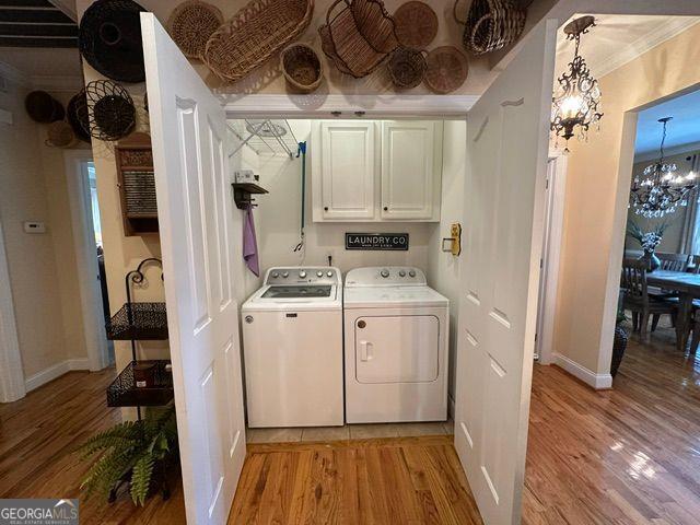 kitchen with ornamental molding, appliances with stainless steel finishes, light stone counters, and light wood-type flooring