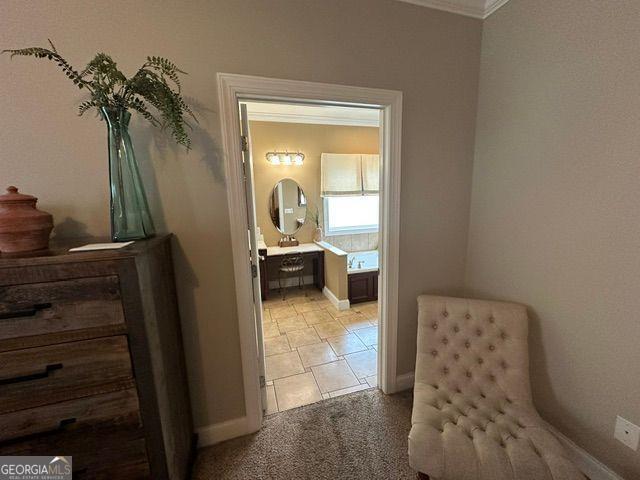 hallway with crown molding and light carpet