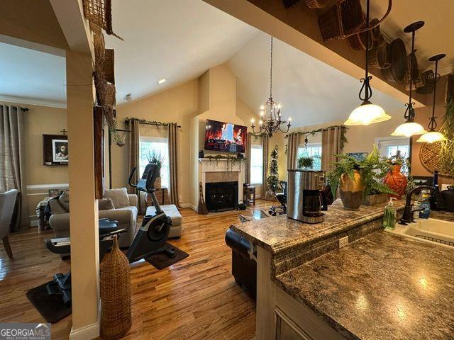 interior space featuring high vaulted ceiling, decorative light fixtures, sink, a notable chandelier, and light hardwood / wood-style flooring