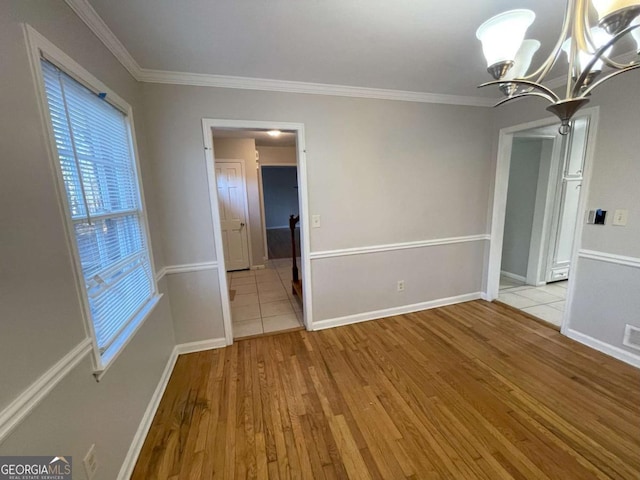 unfurnished dining area featuring a notable chandelier, ornamental molding, baseboards, and light wood-style floors