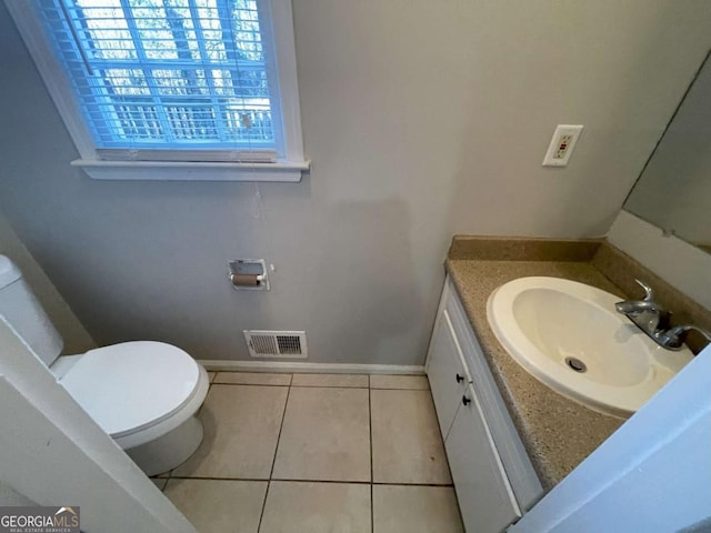 half bath with toilet, vanity, baseboards, visible vents, and tile patterned floors