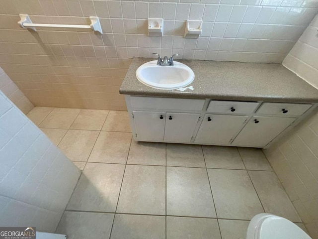 half bath featuring toilet, tile patterned flooring, vanity, and tile walls