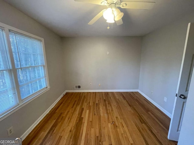 spare room with a ceiling fan, baseboards, visible vents, and wood finished floors