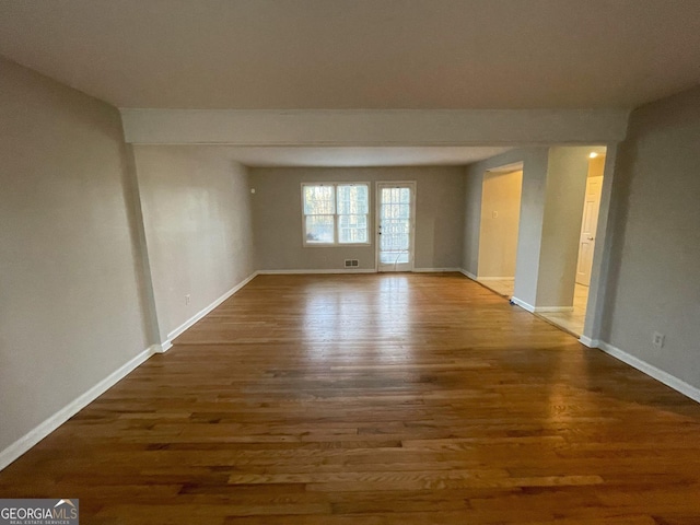 empty room featuring baseboards and dark wood-type flooring