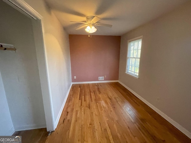 empty room featuring light wood finished floors, visible vents, baseboards, and a ceiling fan