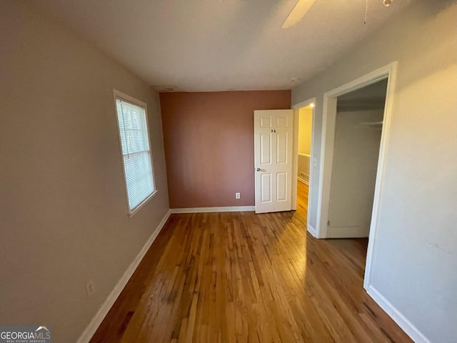 unfurnished bedroom featuring a ceiling fan, a closet, baseboards, and wood finished floors