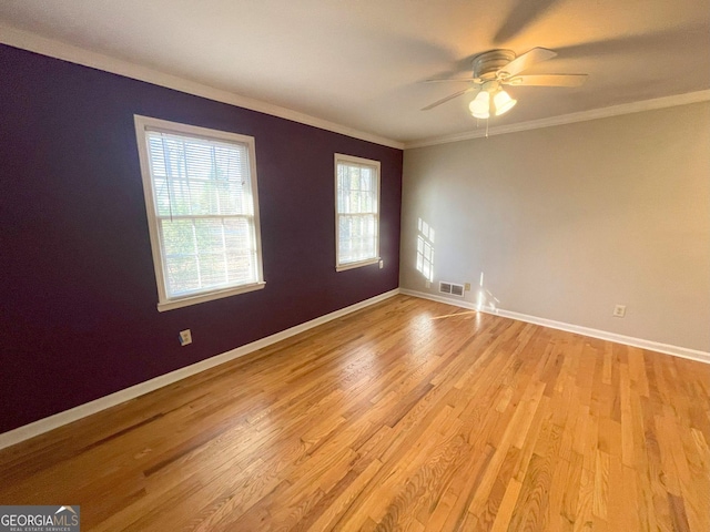 empty room featuring baseboards, ornamental molding, visible vents, and light wood-style floors