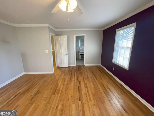 unfurnished bedroom featuring baseboards, a ceiling fan, light wood-style flooring, ensuite bathroom, and crown molding