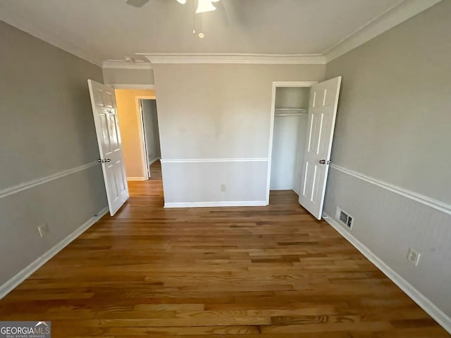 unfurnished bedroom with ceiling fan, ornamental molding, wood finished floors, and visible vents