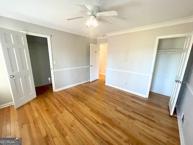 unfurnished bedroom featuring baseboards, a ceiling fan, ornamental molding, wood finished floors, and a closet