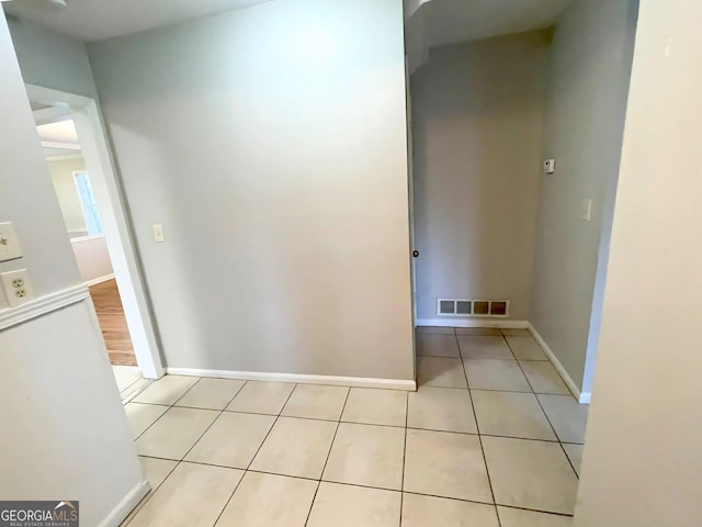 hallway with light tile patterned floors, baseboards, and visible vents