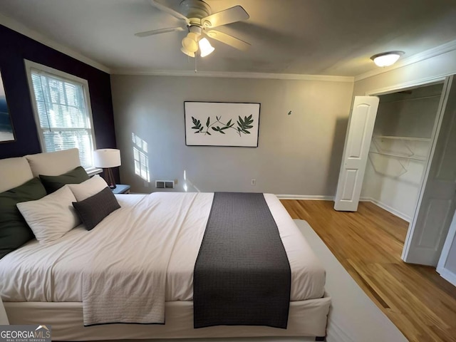 bedroom with baseboards, visible vents, a ceiling fan, ornamental molding, and wood finished floors