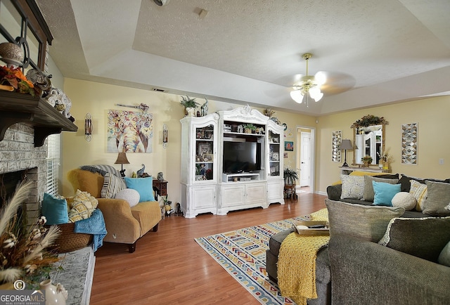 living room with a raised ceiling, hardwood / wood-style floors, and a textured ceiling