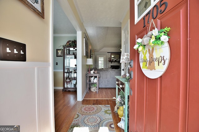 entryway with dark wood-type flooring, ornamental molding, a fireplace, and a textured ceiling