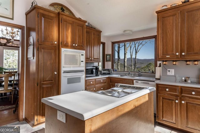 kitchen featuring lofted ceiling, sink, a mountain view, a kitchen island, and white appliances