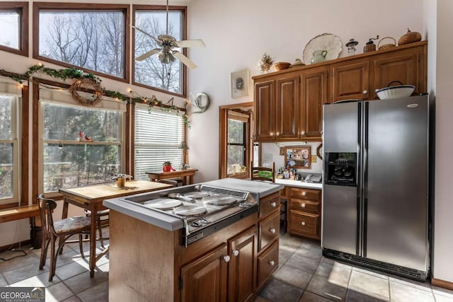 kitchen with a high ceiling, a kitchen island, ceiling fan, and appliances with stainless steel finishes