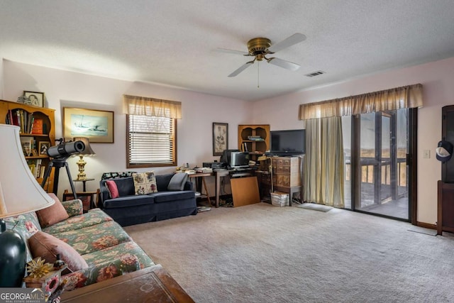 living room with light carpet, ceiling fan, and a textured ceiling