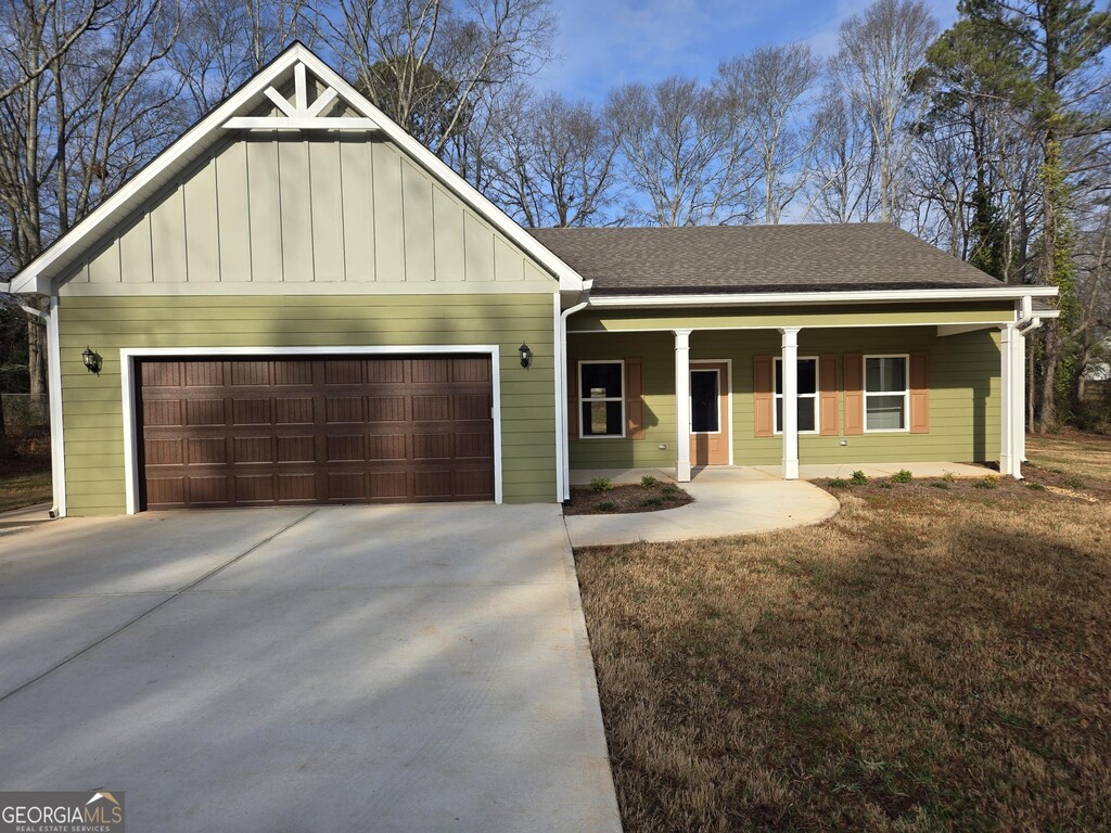 view of front of home featuring a garage, covered porch, and a front lawn