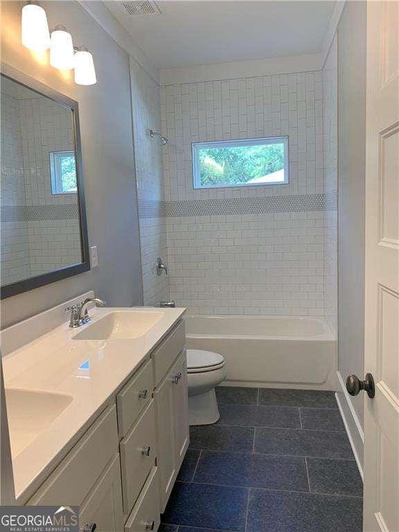 full bathroom with tiled shower / bath, vanity, and toilet