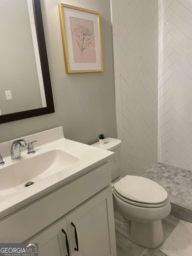 bathroom featuring vanity, toilet, and tiled shower