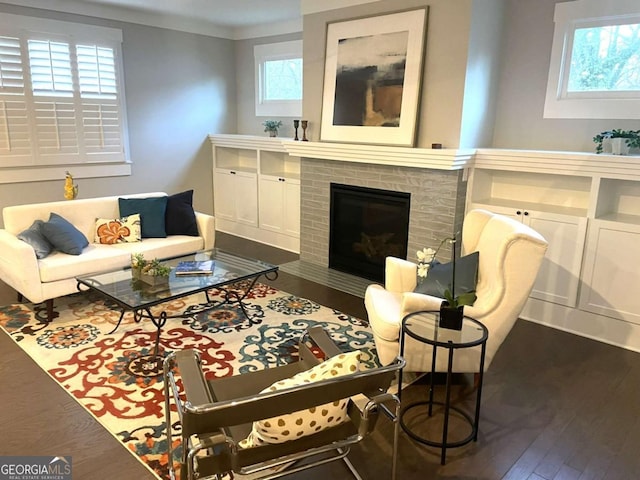 living room with crown molding, plenty of natural light, dark wood-type flooring, and a brick fireplace