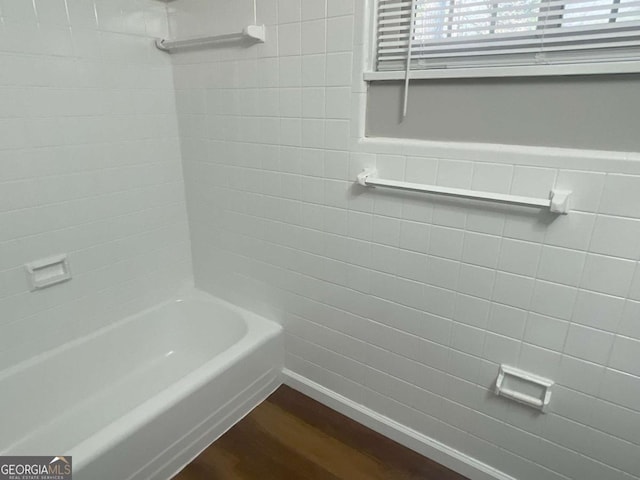 bathroom with tiled shower / bath, hardwood / wood-style floors, and tile walls