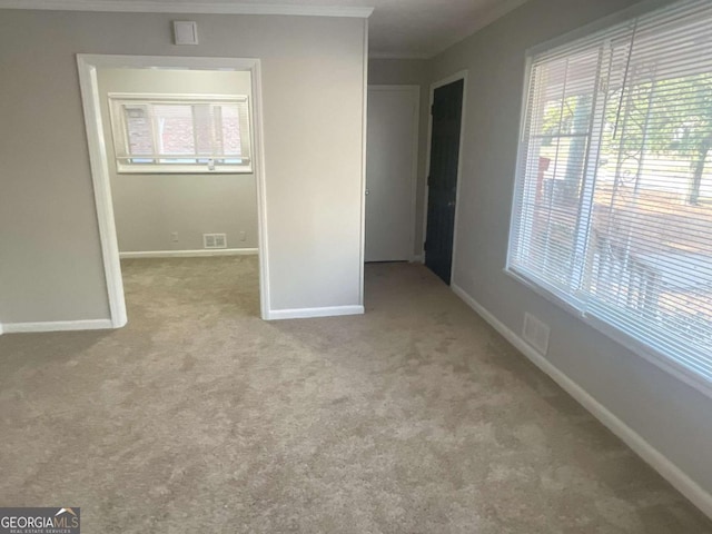 unfurnished room featuring crown molding and light colored carpet