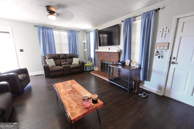 living room with crown molding, ceiling fan, a fireplace, and dark hardwood / wood-style flooring