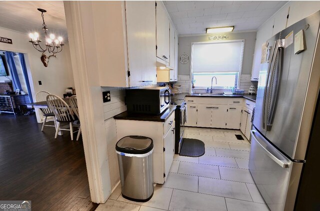 kitchen featuring stainless steel refrigerator, decorative light fixtures, sink, white cabinets, and electric range