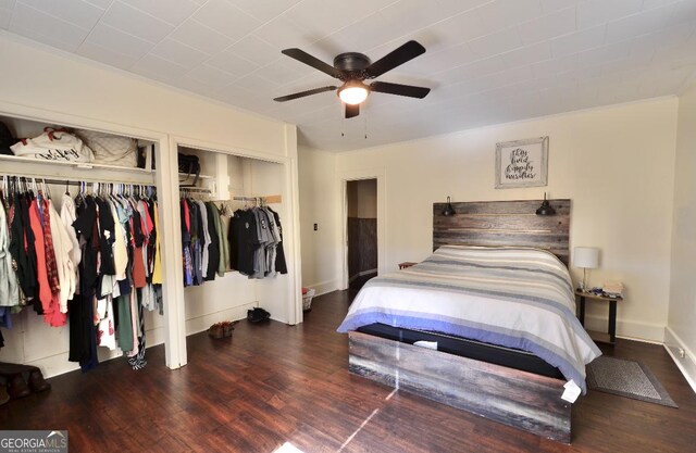 bedroom featuring dark hardwood / wood-style floors, two closets, and ceiling fan