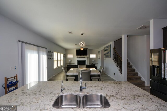 kitchen with dark hardwood / wood-style floors, light stone countertops, sink, and black fridge with ice dispenser