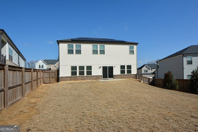 rear view of house with a yard and solar panels