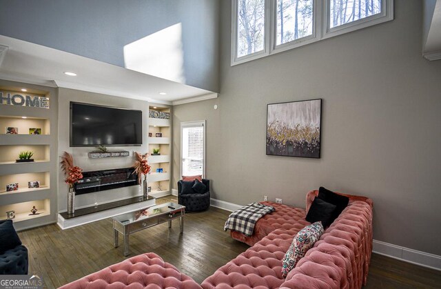 living room featuring a towering ceiling, a fireplace, dark hardwood / wood-style flooring, and built in shelves