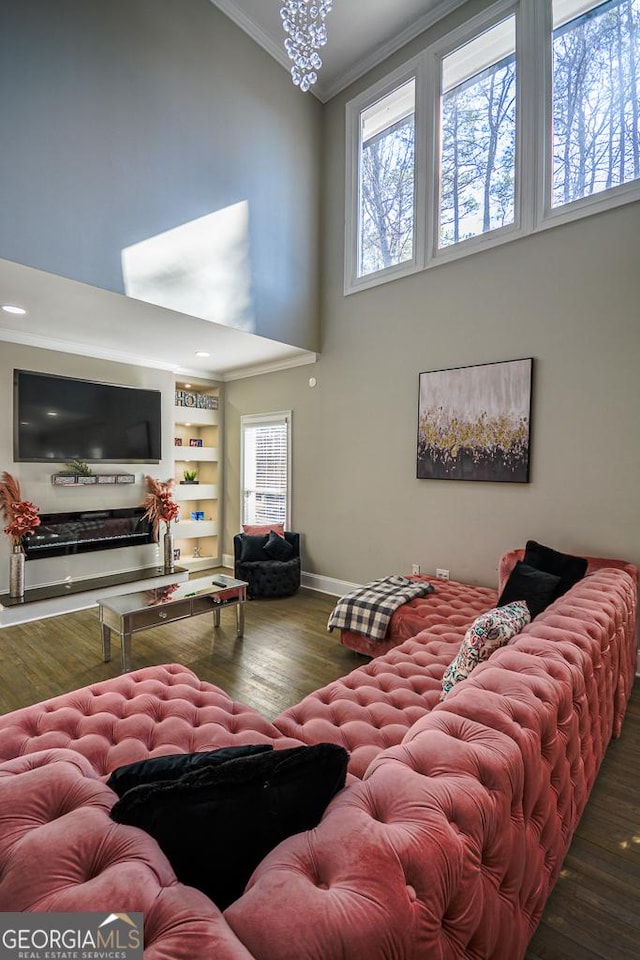 living room with hardwood / wood-style floors, a towering ceiling, and ornamental molding