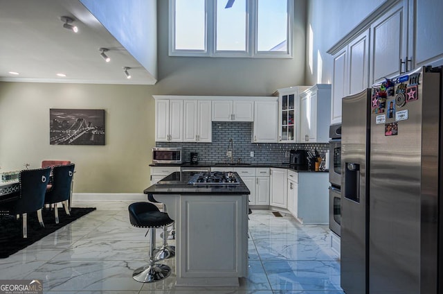 kitchen with backsplash, a kitchen breakfast bar, stainless steel appliances, a center island, and white cabinets