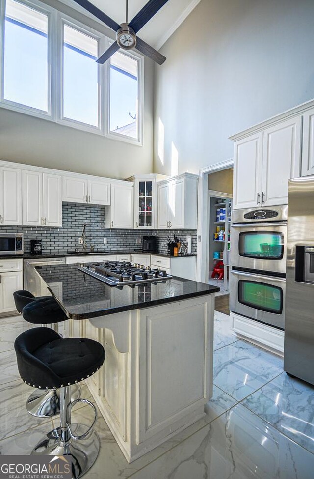 kitchen featuring white cabinetry, dark stone countertops, a kitchen breakfast bar, a center island, and stainless steel appliances