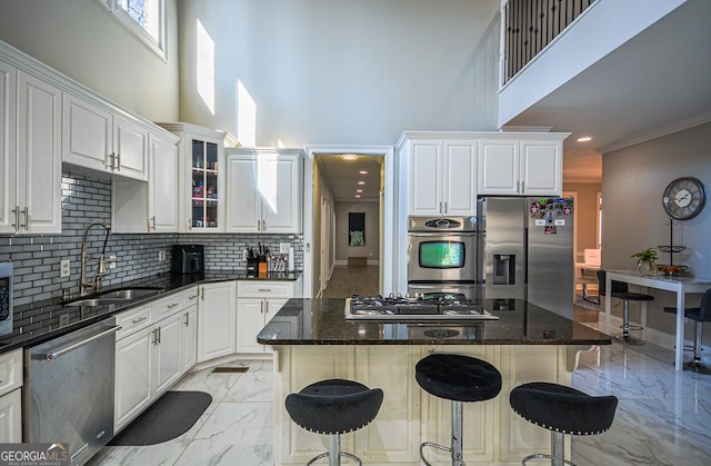 kitchen with a breakfast bar, sink, white cabinetry, dark stone countertops, and appliances with stainless steel finishes