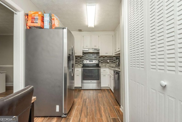 kitchen with appliances with stainless steel finishes, tasteful backsplash, white cabinets, dark wood-type flooring, and a textured ceiling