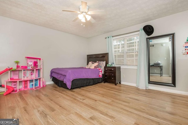 bedroom featuring ceiling fan, a textured ceiling, and light hardwood / wood-style flooring