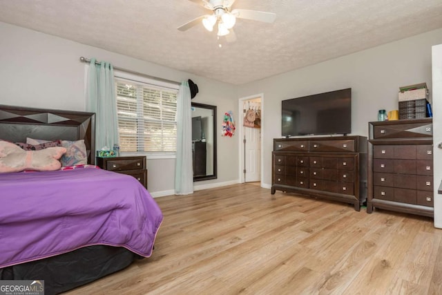 bedroom with ceiling fan, light hardwood / wood-style floors, and a textured ceiling