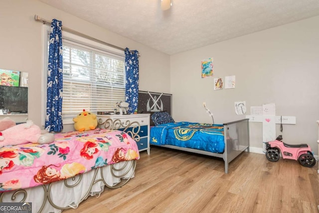 bedroom with ceiling fan, wood-type flooring, and a textured ceiling