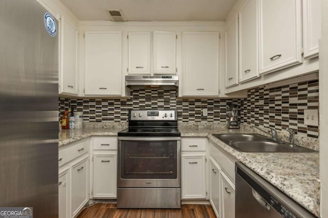 kitchen with appliances with stainless steel finishes, tasteful backsplash, white cabinetry, sink, and dark wood-type flooring