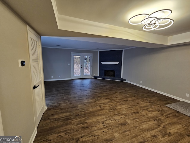 unfurnished living room featuring french doors, dark wood-type flooring, baseboards, and a brick fireplace