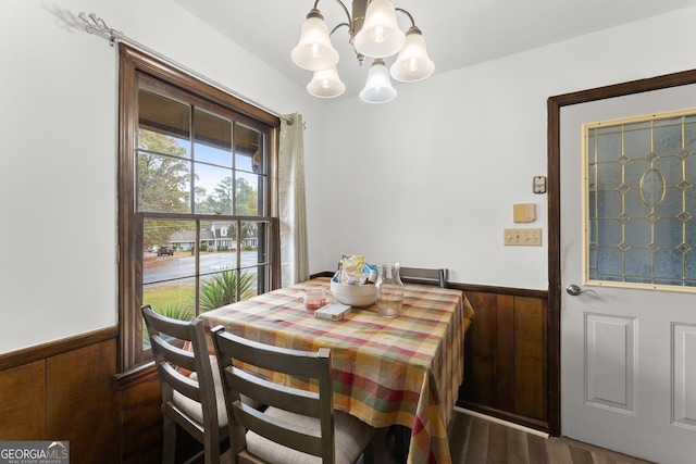 dining area with an inviting chandelier, wooden walls, and dark hardwood / wood-style floors