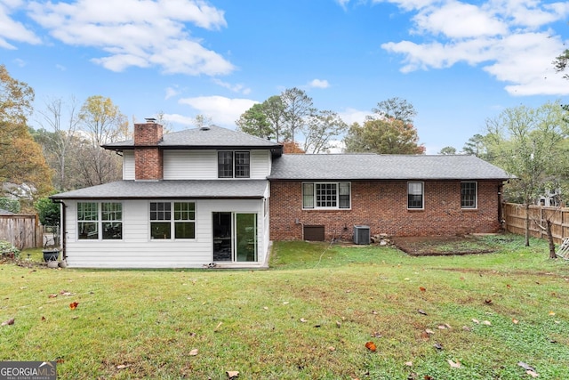 rear view of house featuring central AC and a lawn