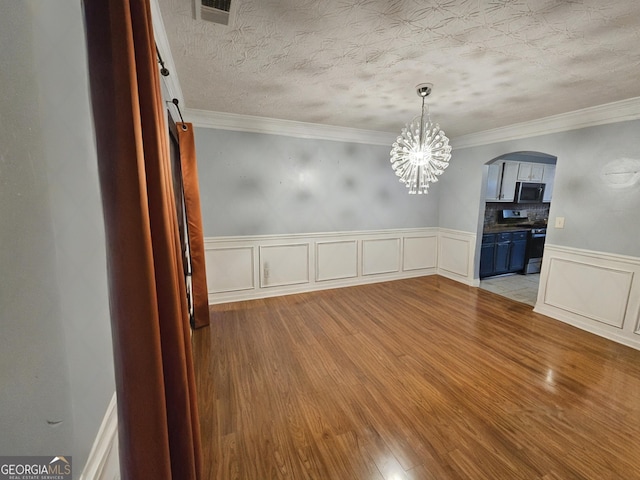 unfurnished dining area with crown molding, a chandelier, a textured ceiling, and light wood-type flooring