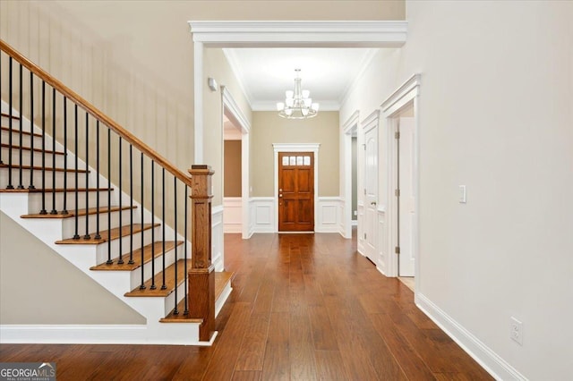 entryway featuring ornamental molding, an inviting chandelier, and dark hardwood / wood-style flooring