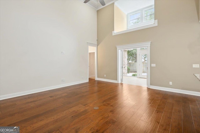 unfurnished living room with ceiling fan, dark hardwood / wood-style flooring, and a towering ceiling